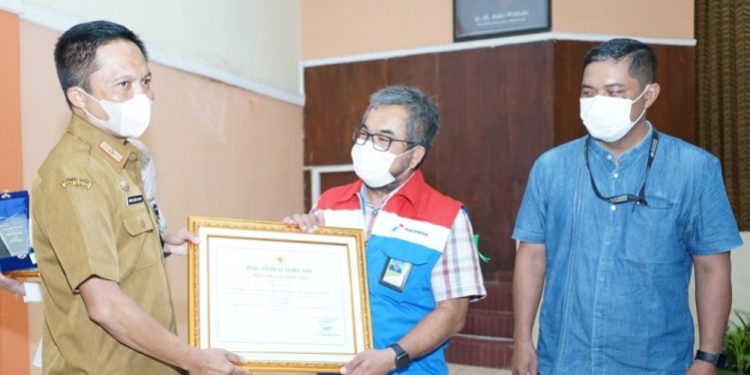 Area Manager Commrel & CSR PT KPI RU IV, Cecep Supriyatna menerima penghargaan TJSLP 2022 Cilacap dari Sekda Cilacap, Awaluddin Muuri. (ISTIMEWA)