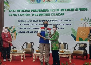GM PUC dan PJ Bupati Cilacap bertukar cinderamata saat pembukaan seminar Aksi Mitigasi Perubahan Iklim Sinergi Bank Sampah. (Wagino/CILACAPMEDIA.com)