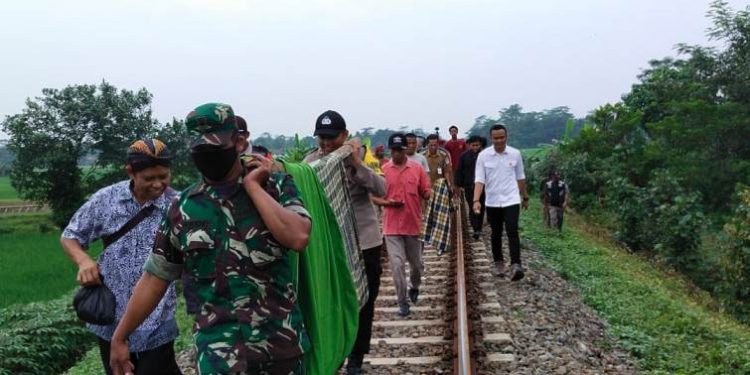 Anggota Polsek Kesugihan bersama anggota TNI mengevakuasi jasad nenek tanpa identitas yang tewas tertabrak KA Lodaya jurusan Bandung-Solo. (ISTIMEWA)
