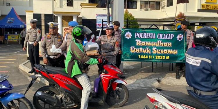 Anggota Polresta Cilacap membagikan takjil gratis kepada pengguna jalan yang melintas di depan Mapolresta. (ISTIMEWA)