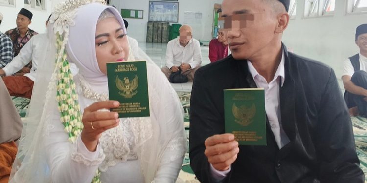 R bersama pasangannya senyum Bahagia seraya menunjukkan buku nikah usai resmi melangsungkan pernikahan di dalam Lapas Kelas II B Cilacap. (ISTIMEWA)