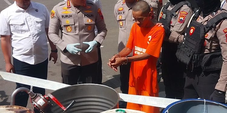 Pemilik usaha oli palsu menunjukkan barang bukti drum penampungan oli bekas usai digerebek saat konferensi pers di Polresta Cilacap. (CILACAPMEDIA/Wagino)