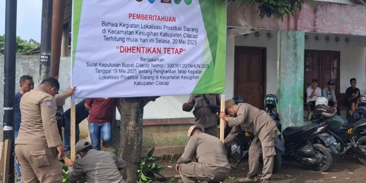 Petugas Satpol PP Cilacap memasang baliho pemberitahuan penghentian tetap lokalisasi di Desa Slarang, Kecamatan Kesugihan, Kabupaten Cilacap, pada Jumat, 23 Mei 2025. (FOTO : ISTIMEWA)